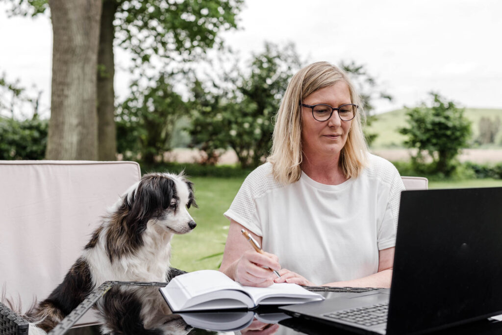 Klaudia Holt, Inhaberin Hundezentrum Holt, und ihr Hund vor dem Laptop